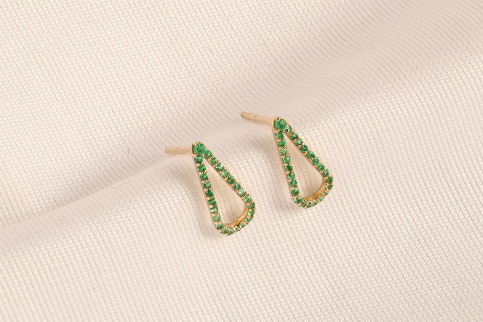 Emerald earrings on softly woven fabric